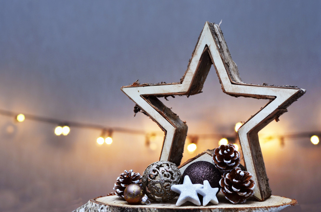 Ein Stern aus Holz mit Weihnachtsdeko, im Hintergrund eine Lichterkette