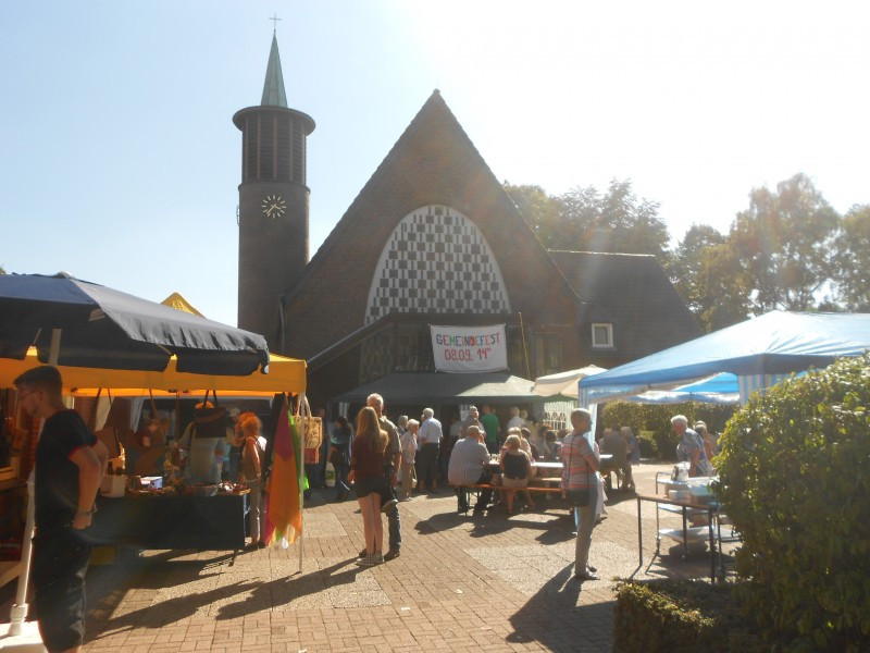 Menschen an bunten Ständen auf dem Kirchvorplatz